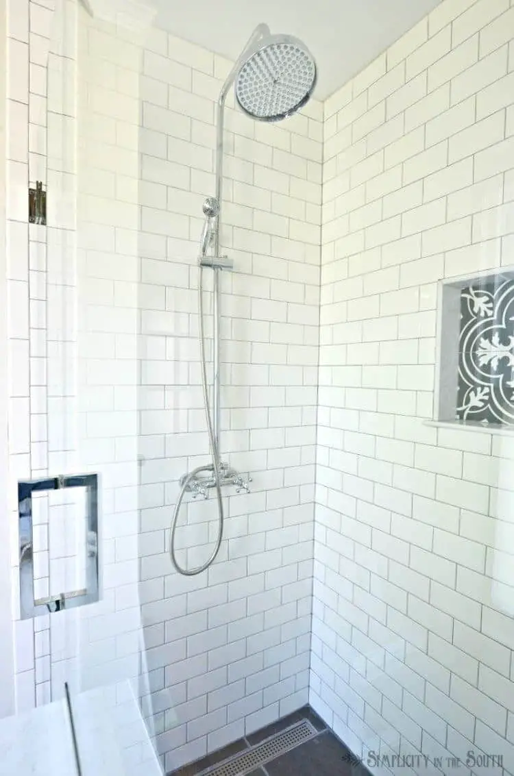White subway tile shower with rain shower head and cross handles